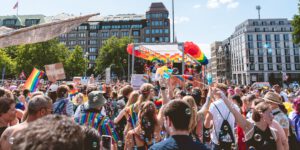 CSD Hamburg 2022, eine Menschenmenge umringt einen der Paradewagen, der mit bunten Luftballons in Regenbogenfarben dekoriert ist.