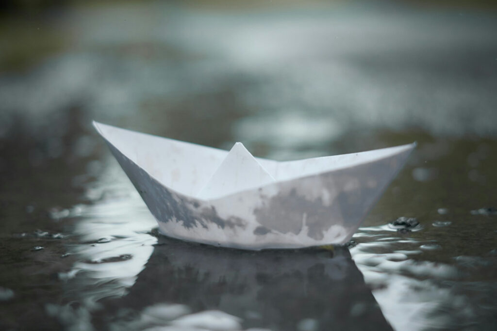 Ein kleines Papierfaltboot im Regen in Nahaufnahme