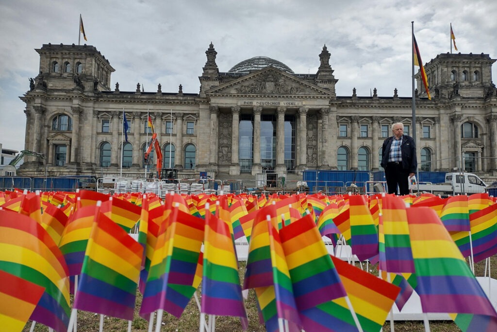 Viele kleine Regenbogenfähnchen sind auf der Rasenfläche vor dem Reichstaggebäude platziert worden. Symbolbild für Artikel "CSD Berlin 2025: Queere Sichtbarkeit braucht Sicherheit anstatt Symbole auf dem Reichstag"