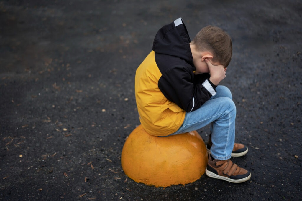 ein Junge sitzt auf einer Halbkugel und wirkt leidend. Symbolbild für Artikel "Pädo-Skandal: Ralf Dose und seine Verstrickungen mit Helmut Kentler".