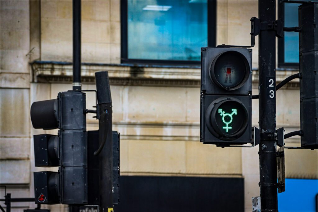 Eine Fußgänger-Ampel zeigt ein grünes Trans-Symbol, Bild zu Artikel "Ein Jahr Selbstbestimmungsgesetz: Alles gut?"