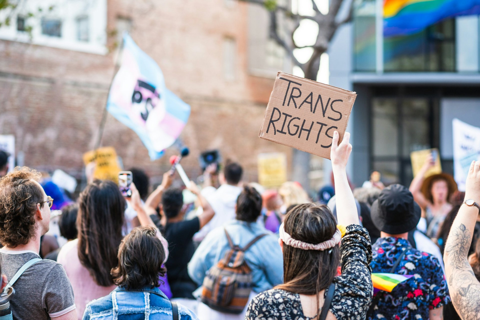 Demonstration für Transrechte, eine Transflagge wird hochgehalten, auf einem Schild steht "Trans Rights".