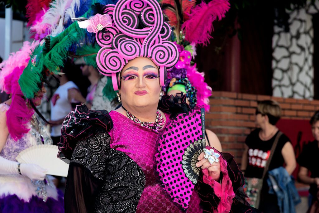 Drag Queen in einem aufwendig gestalteten Kostüm mit Pink und Schwarz und einem Kopfschmuck auf Schaumgummi. Symbolbild für Artikel "Sind Drag-Lesungen das Nonplusultra der Vielfaltserziehung?"