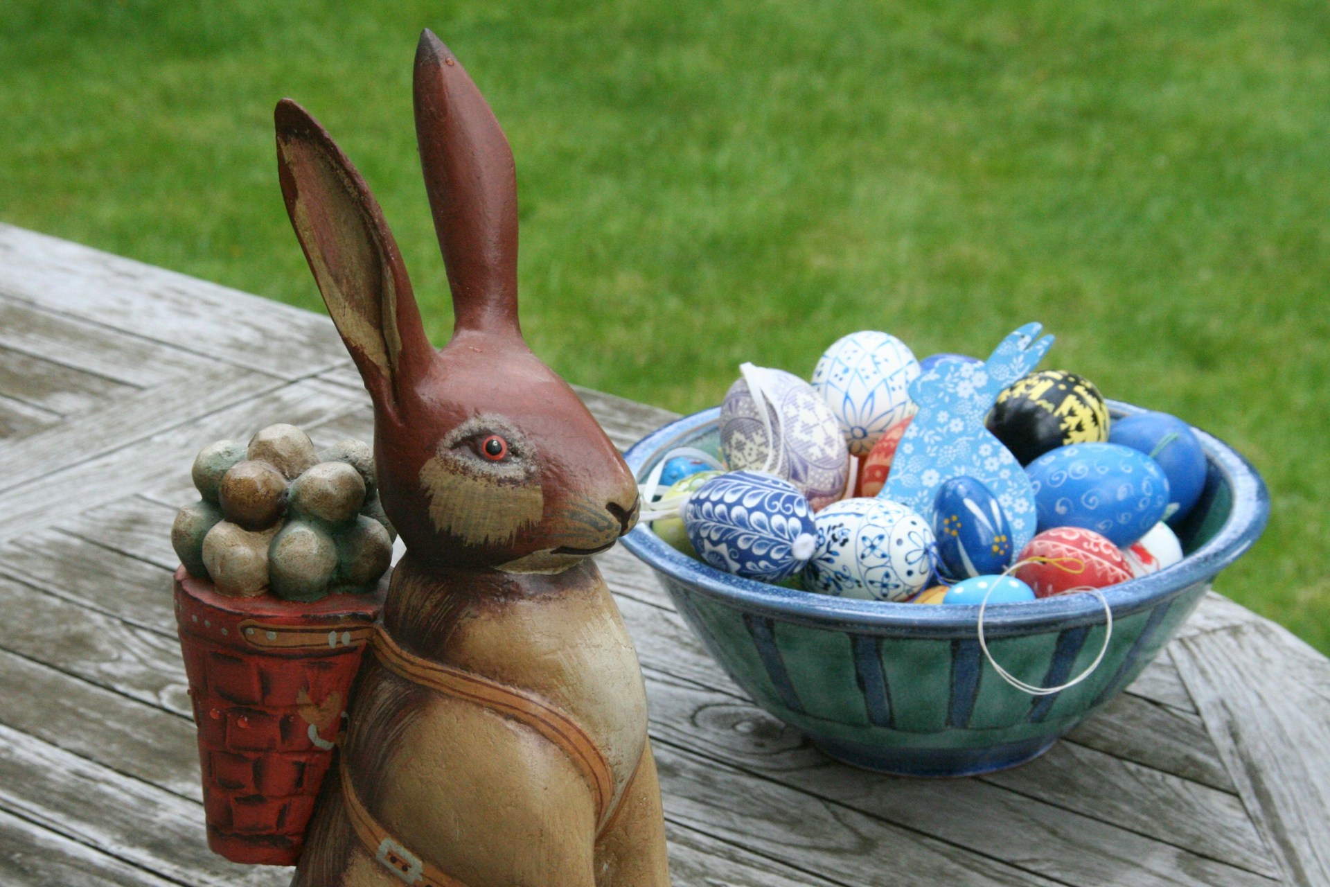 Eine Osterhasenfigur sitzt vor einem blauen Korb mit Ostereiern. Symbolbild für Artikel "Zwei erhellende Texte zur Debatte um „Queer“ vs. „Schwul“"